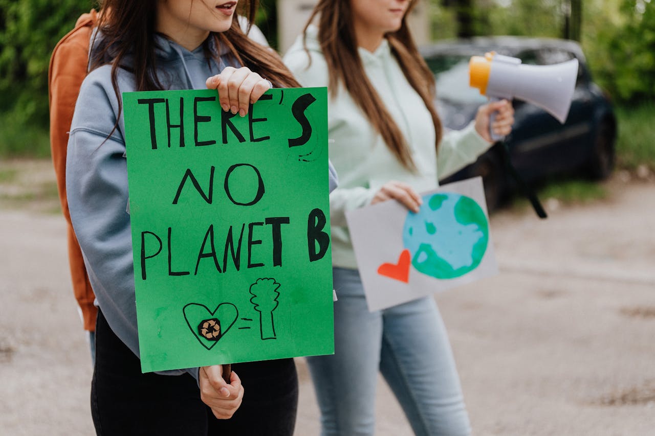 Young adults at a climate change protest holding eco-friendly posters outdoors.