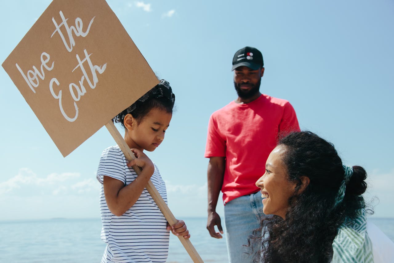 Family promoting love for Earth with a placard at a sunny beach.